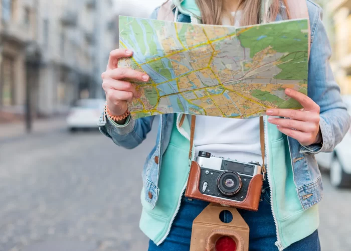 mid-section-female-traveler-with-camera-holding-map-hand